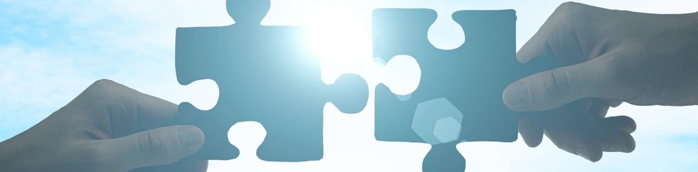 Hände fügen zwei Puzzleteile zusammen als Symbolbild für Full-Service-Dienstleister in der IT